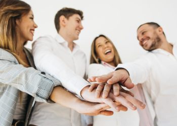 companeros-trabajo-sonrientes-oficina-que-ponen-manos-juntas