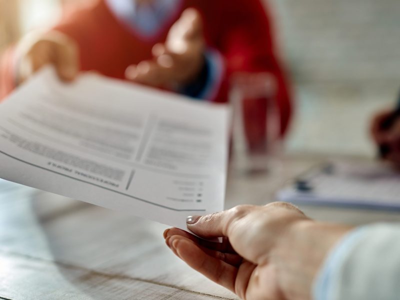 Close-up of job applicant giving his resume during job interview in the office.